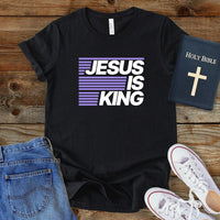 a t - shirt that says jesus is king next to a pair of jeans and