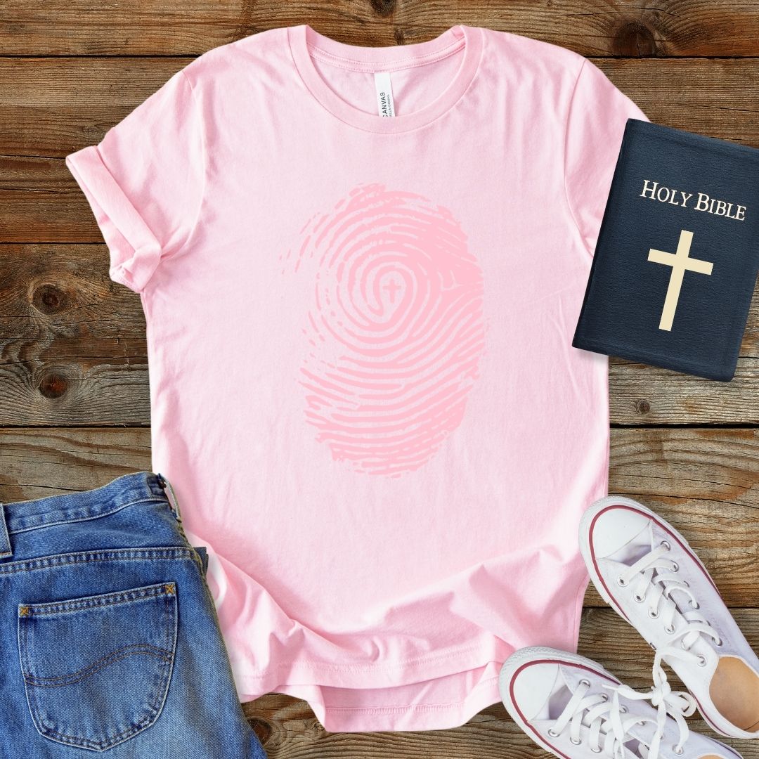 a pink t - shirt with a cross and a bible next to it